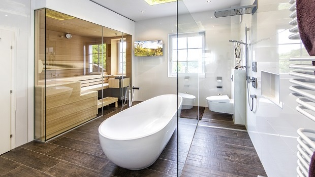 So geht Wellness zuhause: Eine freistehende Badewanne für zwei, eine große, bodenebene Dusche und eine moderne Saunakabine bieten in diesem Badezimmer Möglichkeiten zur Entspannung